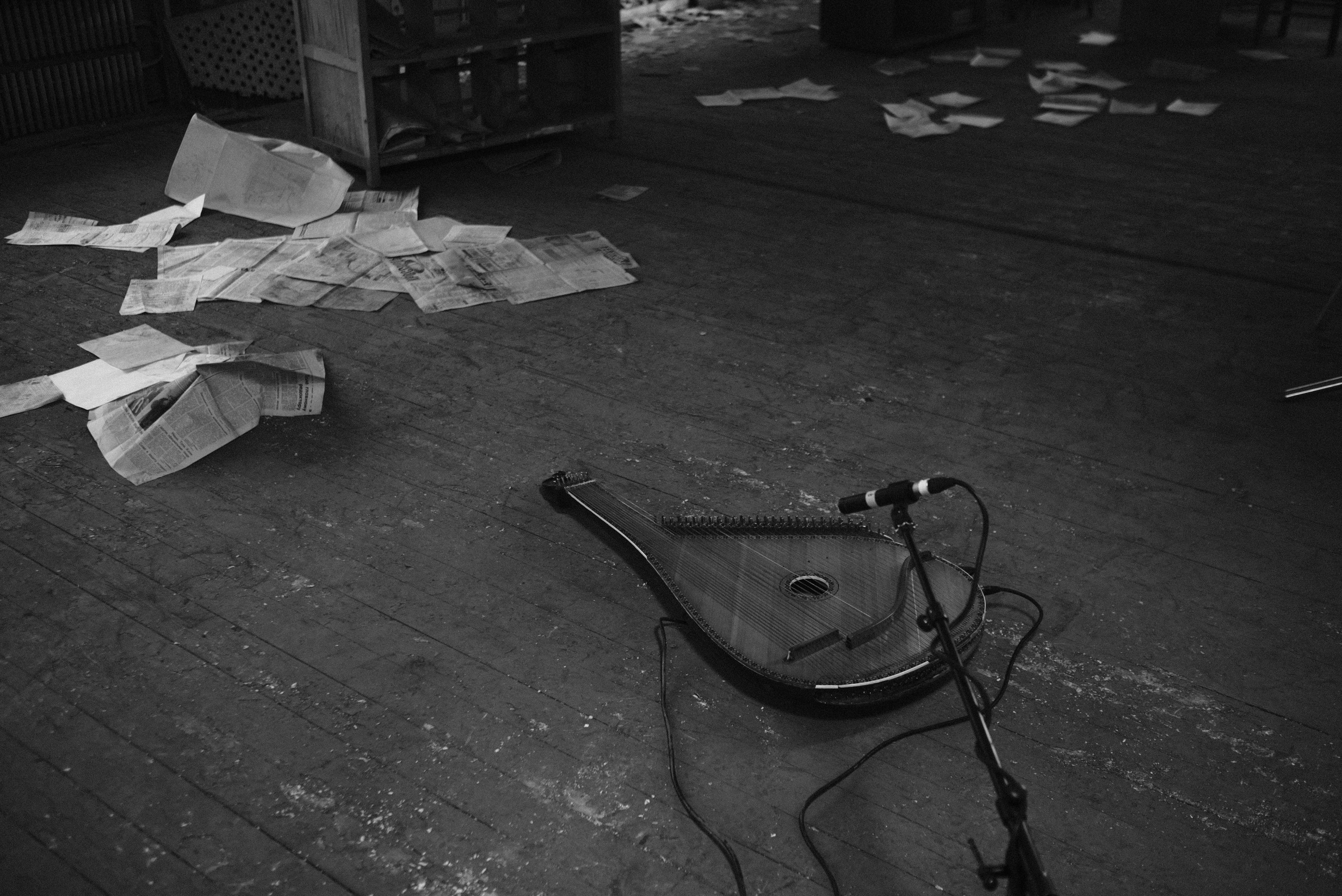 A bandura and scattered papers on a floor