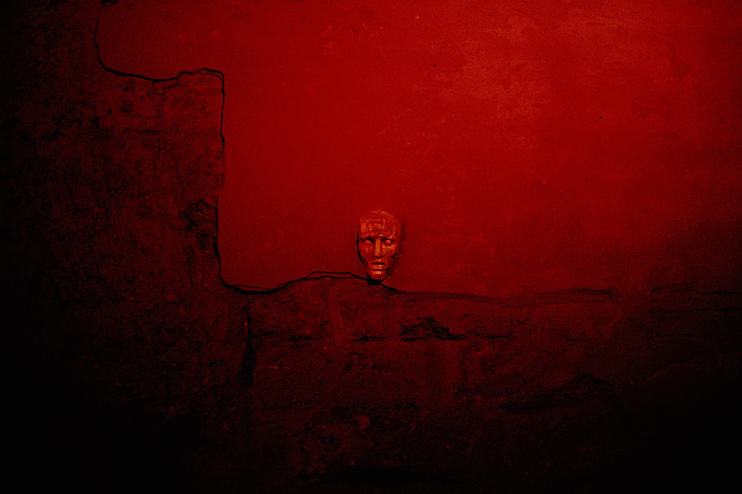 A small face-like mask on a red wall