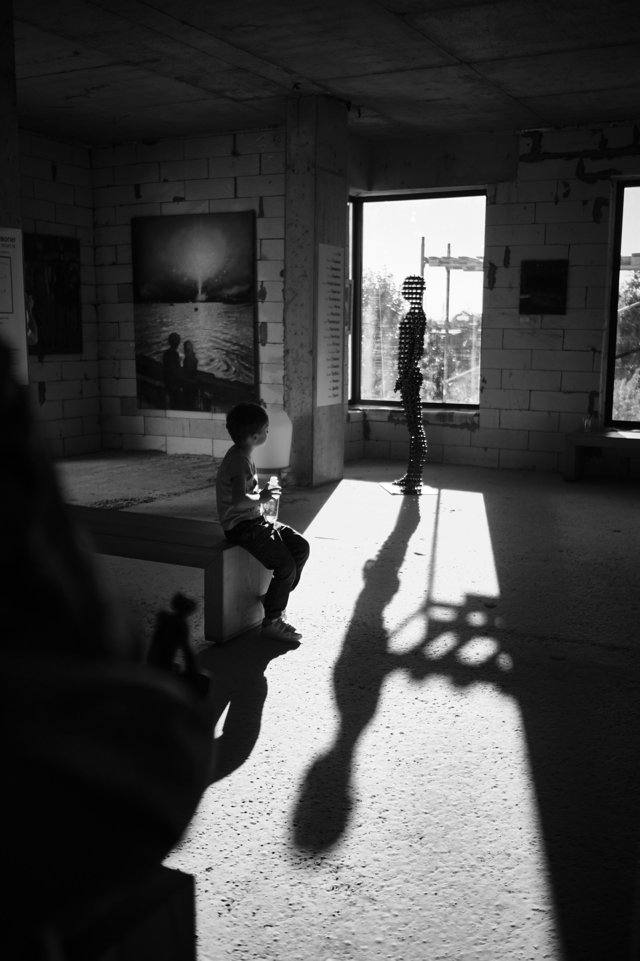 A child sitting in an exhibition space with long shadows